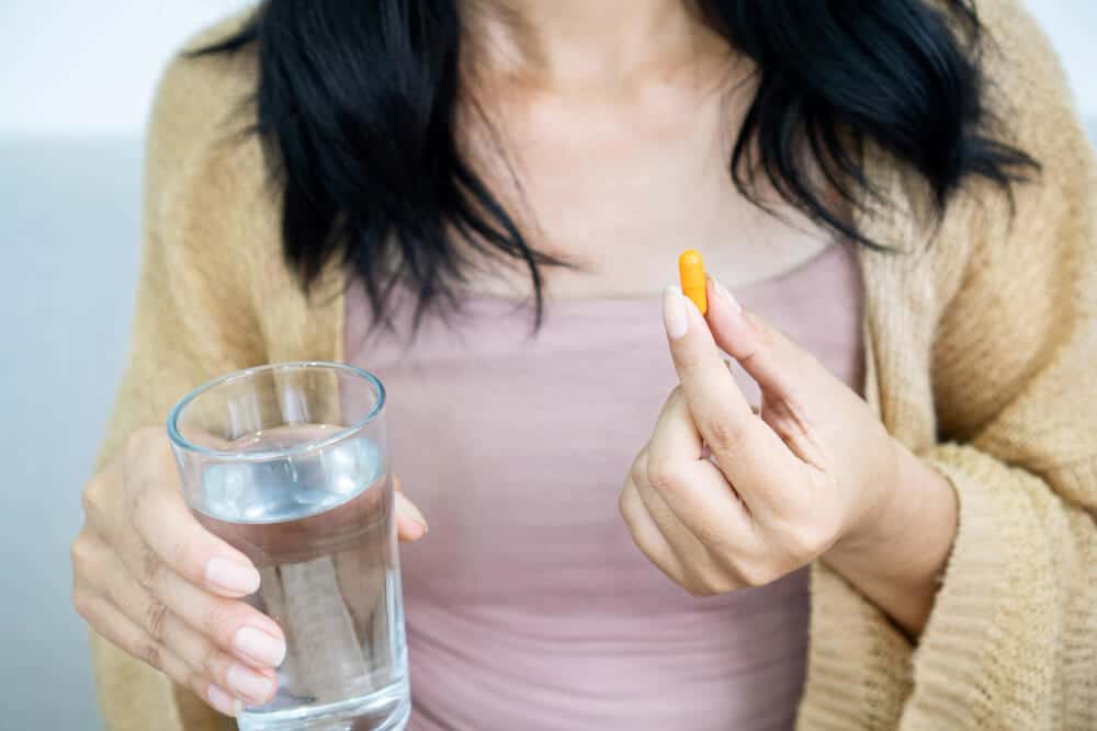woman hand holding turmeric supplement pill